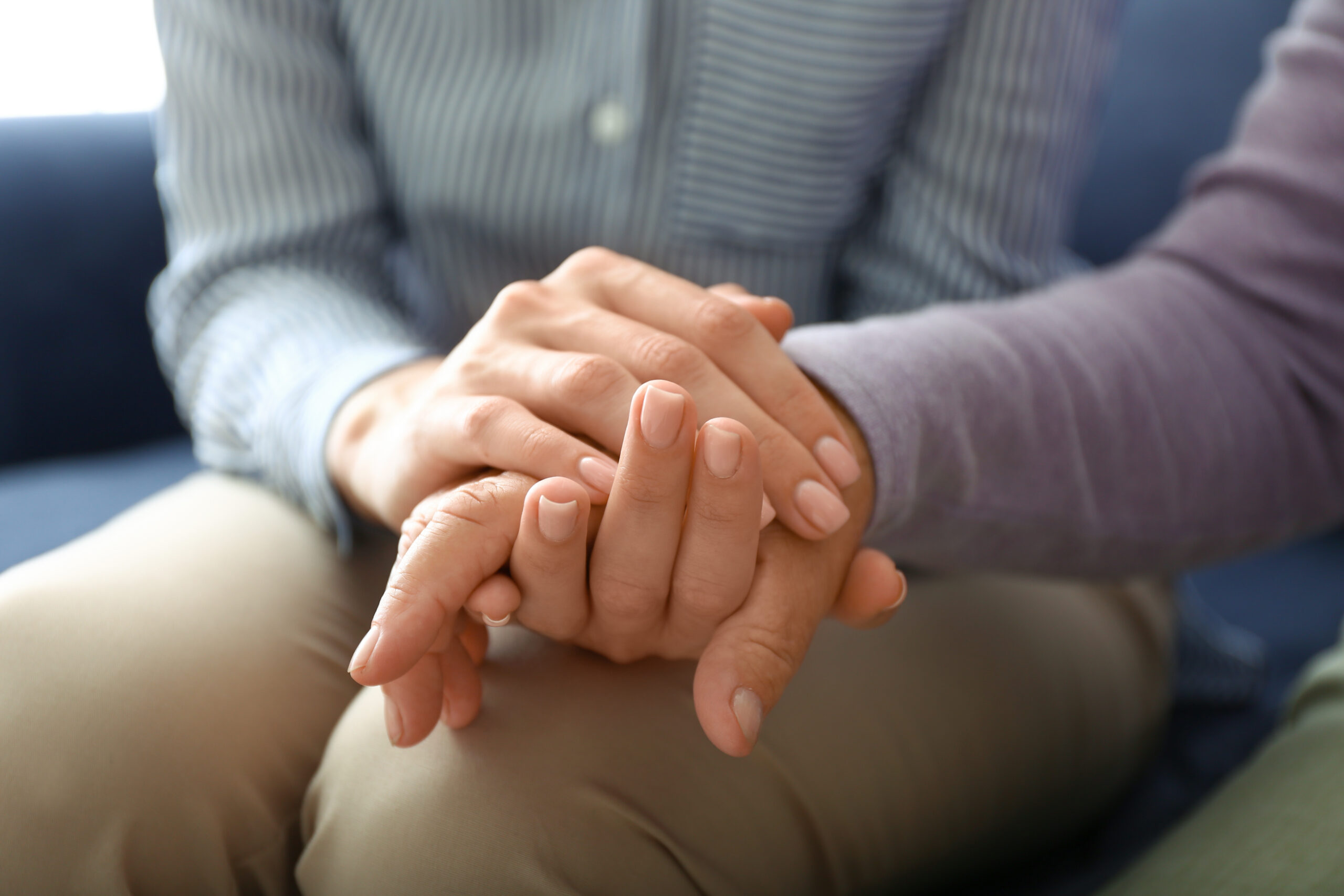 Young daughter supporting elderly mother at home, closeup